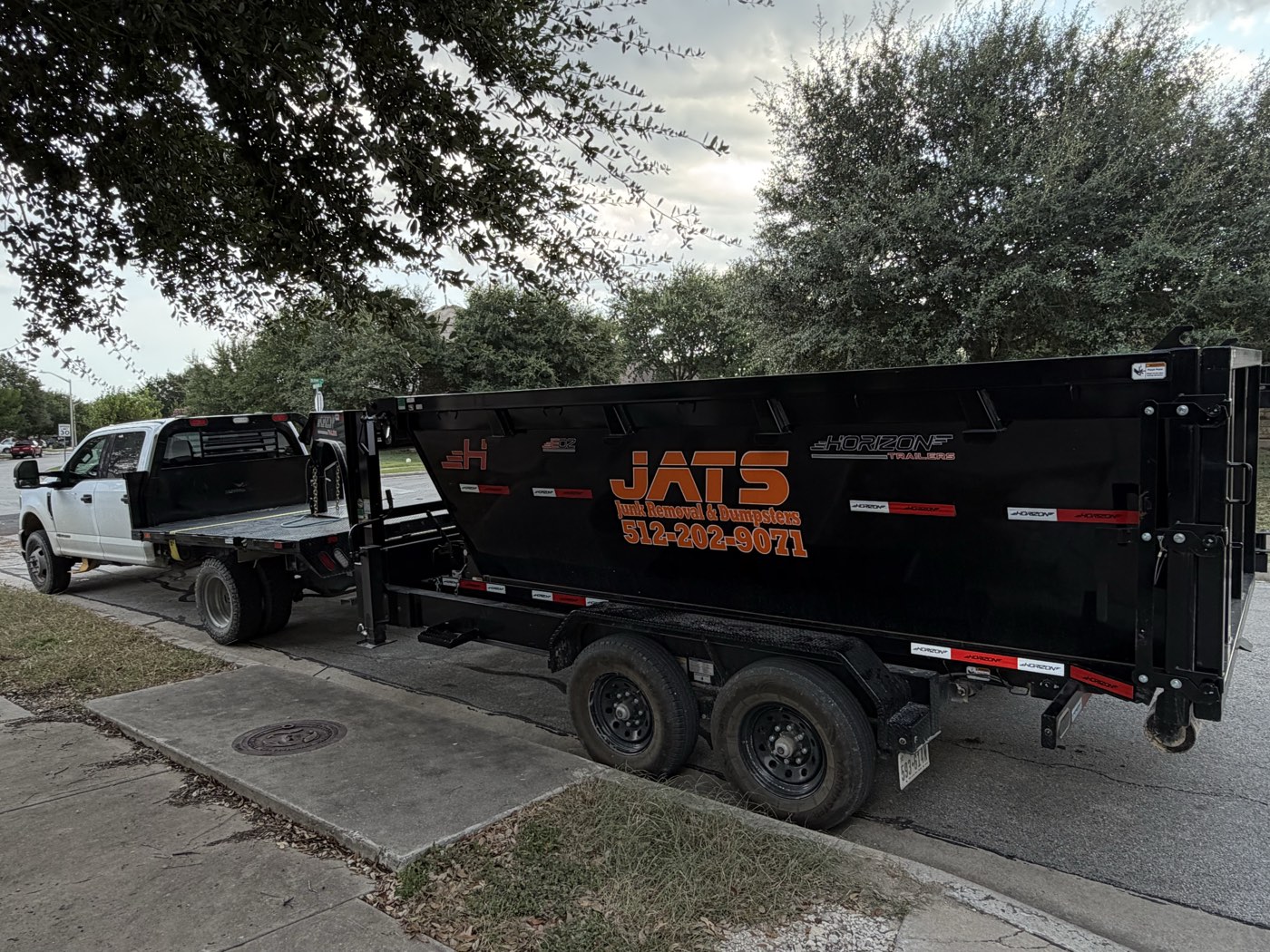 JATS truck and gooseneck trailer hauling a 15-yard dumpster to a job in San Marcos, Texas