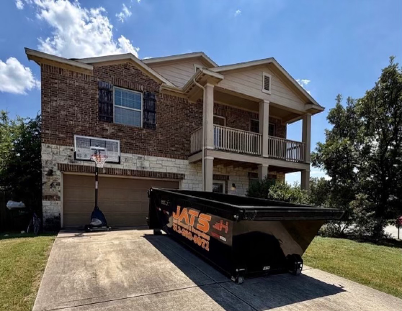JATS 15-yard dumpster set in a residential driveway in San Marcos, Texas