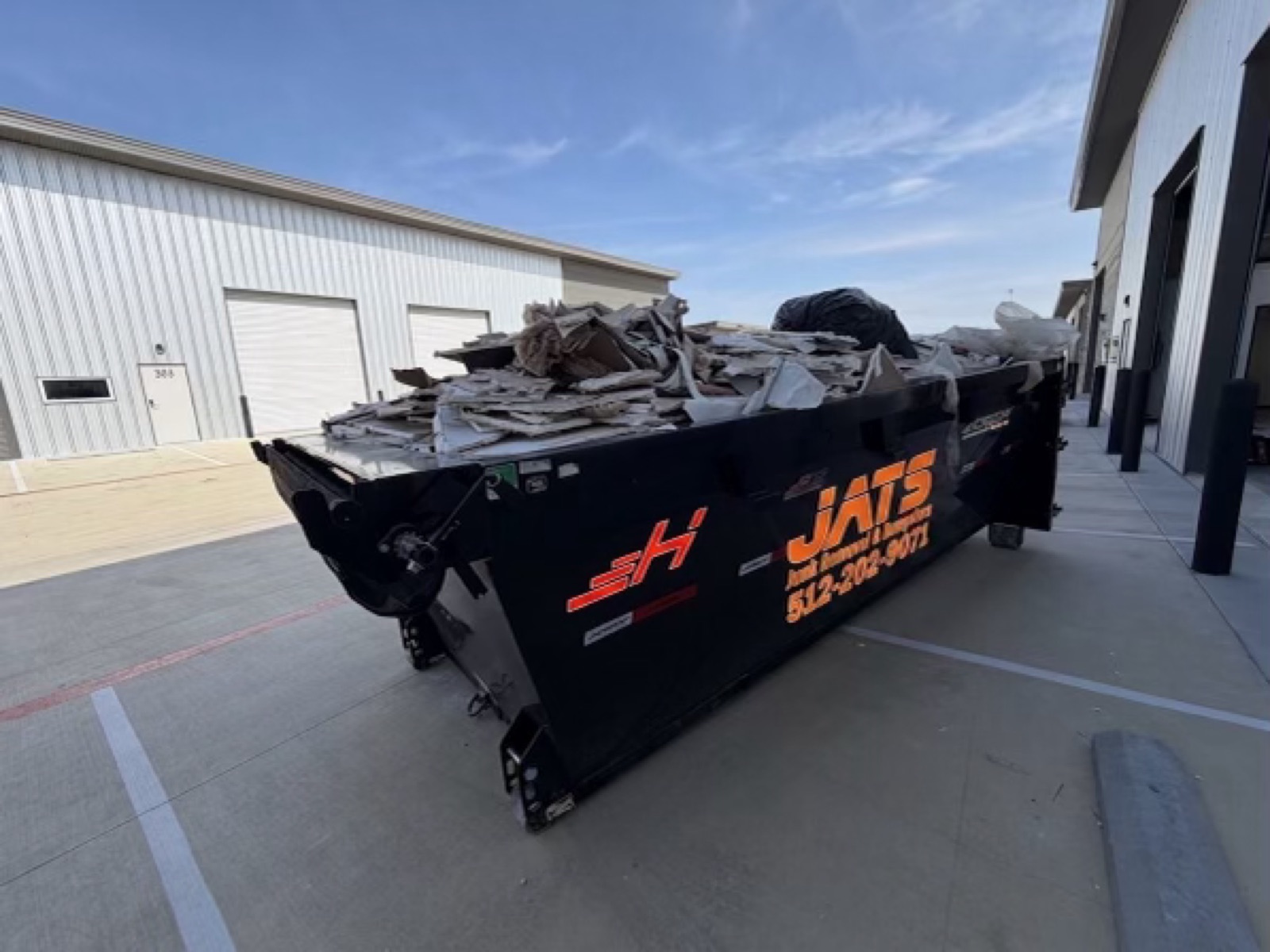 JATS 15-yard dumpster loaded with remodeling debris on a job site